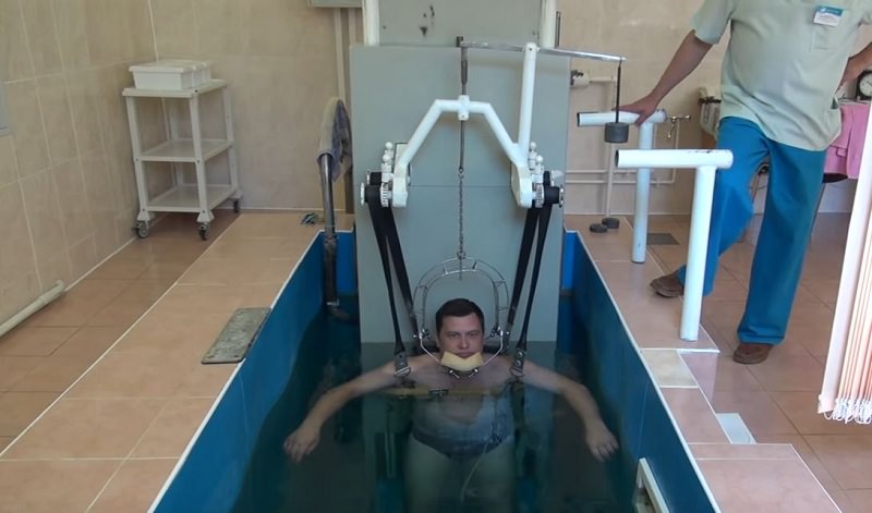 Мужчине в бассейне вытягивают позвоночник.